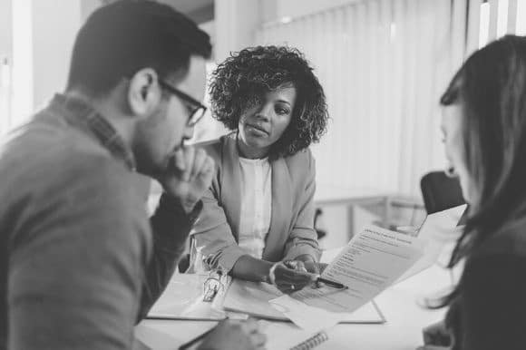 An accounts payable and receivable clerk showing a balance sheet to her colleagues.