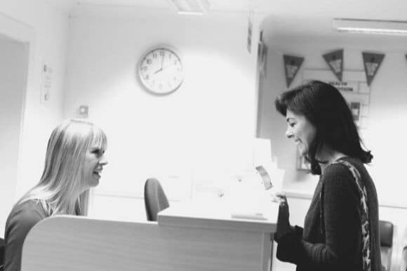 Admissions coordinator talking with hospital visitor at desk