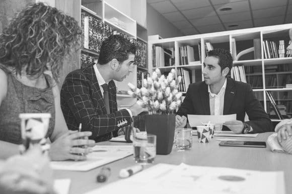 Communications director sitting down at a table with colleagues to discuss strategy.