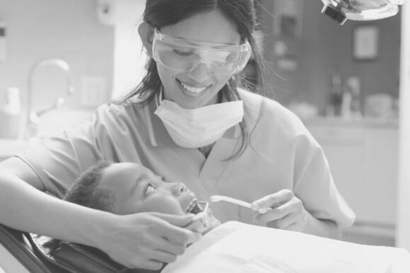 Dental hygienist cleaning a patient's teeth in dental office