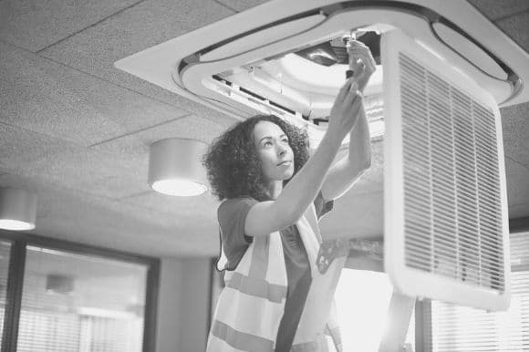 A facilities manager repairs an HVAC system in an office.