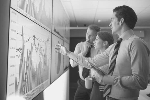 A financial planning analyst, with two colleagues, going over financial data.