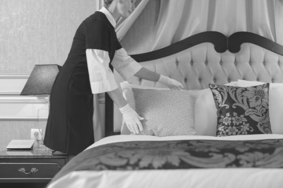 Housekeeping worker making the bed in a guest room.