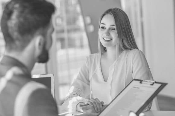 A company's HR director sits with a new employee to help her get onboarded.