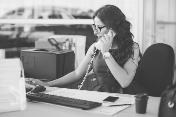 Legal secretary talking on the phone while sitting at her desk in a law firm.