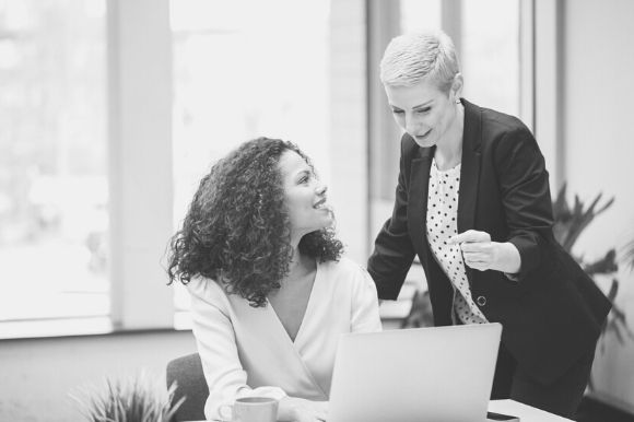 Personal assistant talking with boss at desk