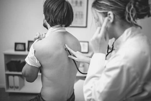 A respiratory therapist checks a patient's breathing with the help of a stethoscope.