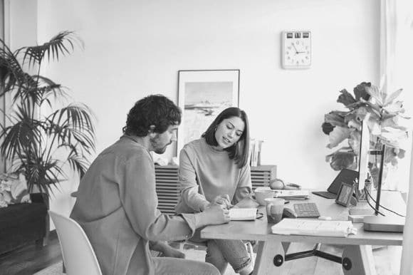 A scheduler, sitting at a desk and going over meeting times with her manager.