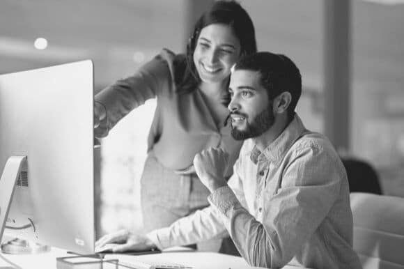 Technical trainer assisting employee at computer