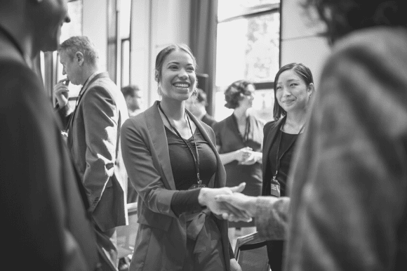 Business development director at a networking event, shaking hands with another person.