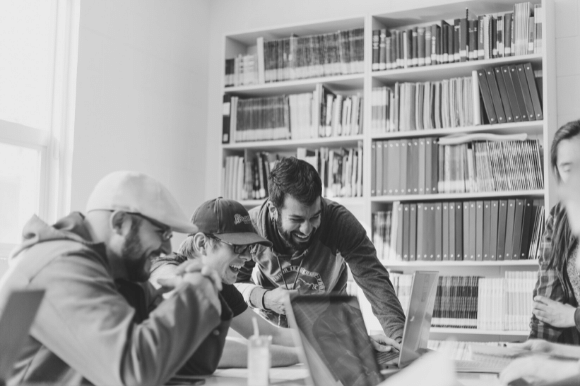 Three coworkers laughing and enjoying each others' company, no doubt the result of well-implemented employee morale boosters.