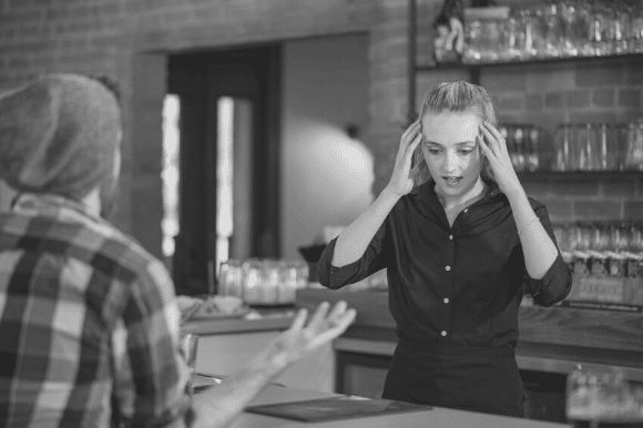 Cashier dealing with employee stress, as an impatient customer complains.