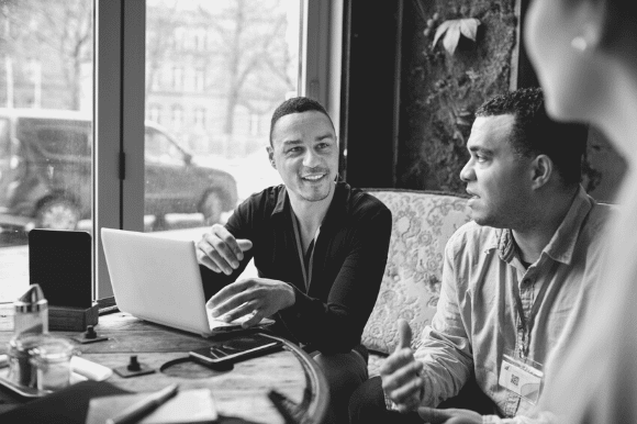 Two siblings working together at a table, demonstrating how hiring friends and family can sometimes work out.