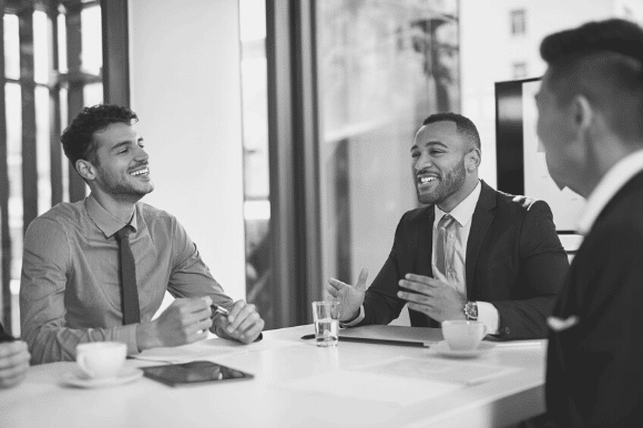 Manager sitting at a table and motivating employees with animated hand gestures.